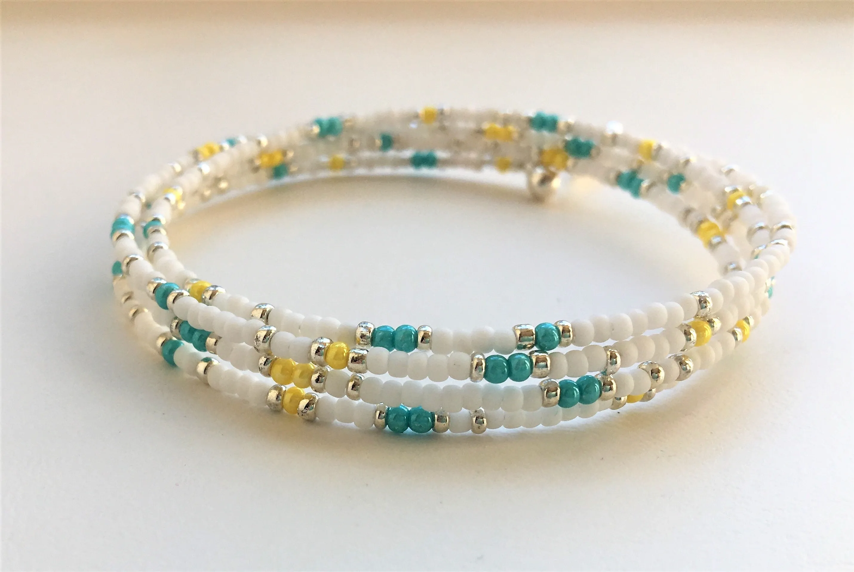 Beaded memory wire bracelet - white, turquoise, yellow and silver beads with angel wing pendant