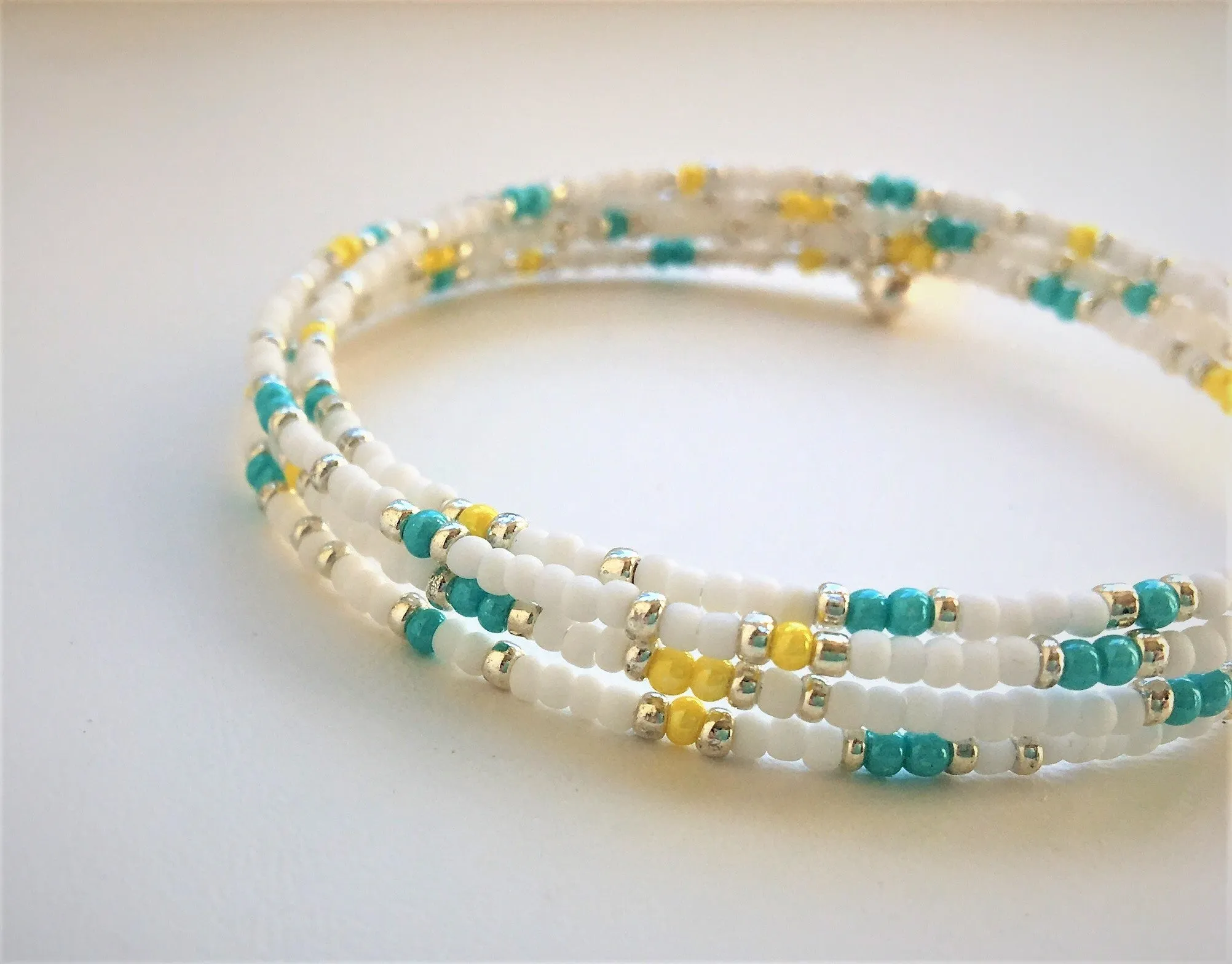 Beaded memory wire bracelet - white, turquoise, yellow and silver beads with angel wing pendant