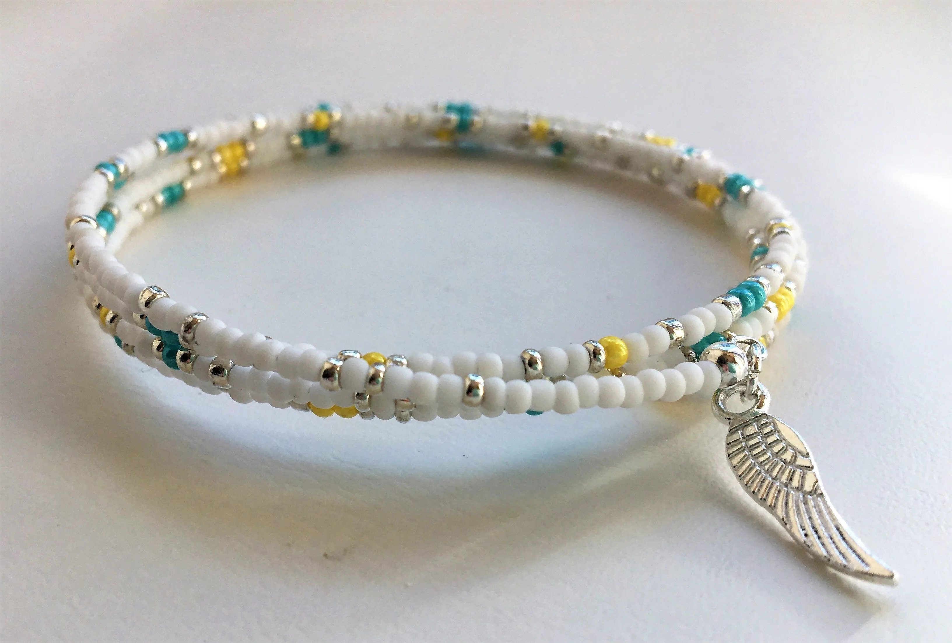 Beaded memory wire bracelet - white, turquoise, yellow and silver beads with angel wing pendant