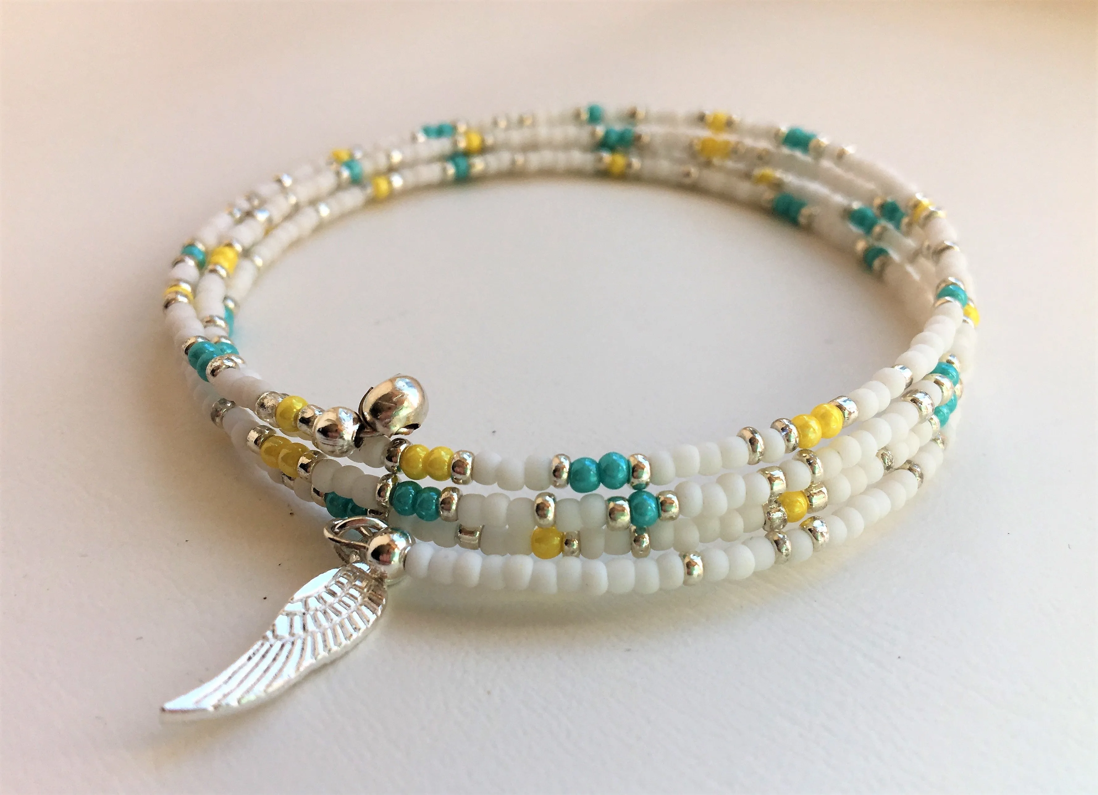 Beaded memory wire bracelet - white, turquoise, yellow and silver beads with angel wing pendant